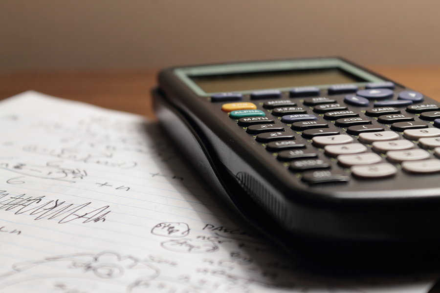 Taschenrechner auf handgeschriebenen mathematischen Notizen auf einem Schreibtisch