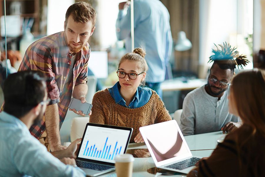 Junges Team bei einer Besprechung in modernem Büro mit Laptops und Diagrammen