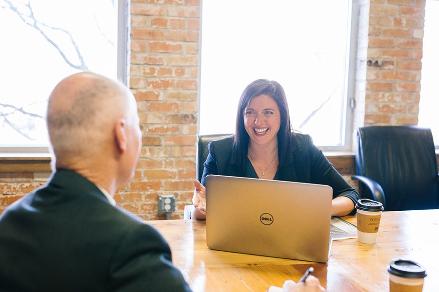 Geschäftsfrau in freundlichem Gespräch mit einem Kollegen in modernem Büro