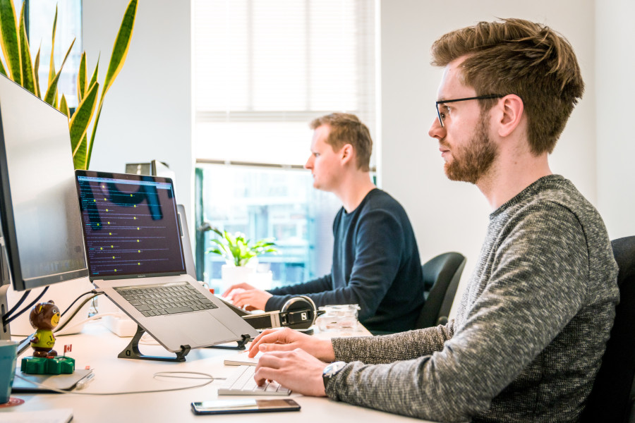 Zwei Männer im Büro sitzen konzentriert am PC
